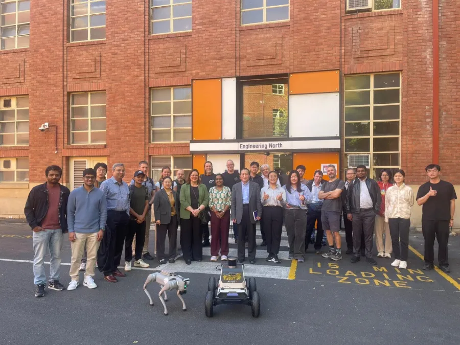 Group photograph from the Drone and Robotics Workshop at Adelaide University with robotics equipment displayed in front.